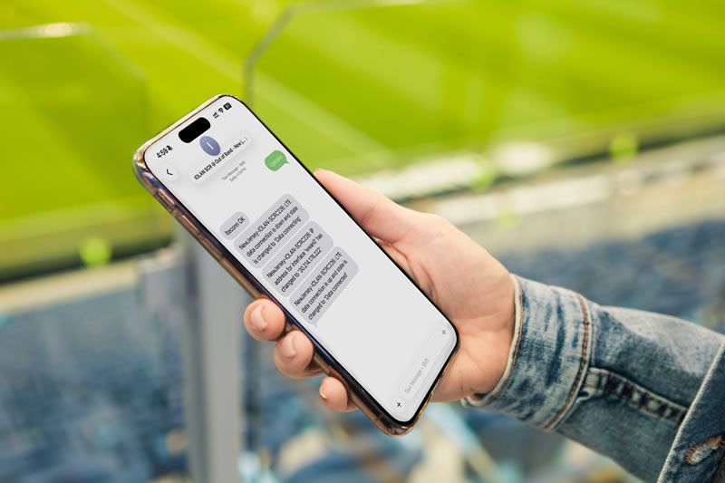Hand holding a smartphone in a sports stadium sending text messages to IOLAN SCRC to enable a cellular connection