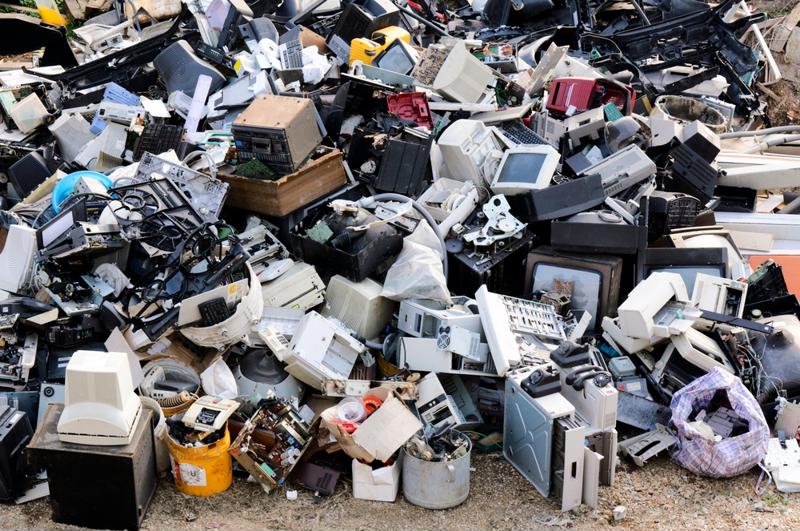 A pile of old and broken electronics at a dump.