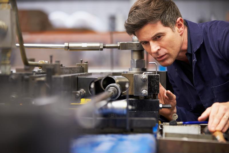 Male worker calibrating manufacturing equipment. 