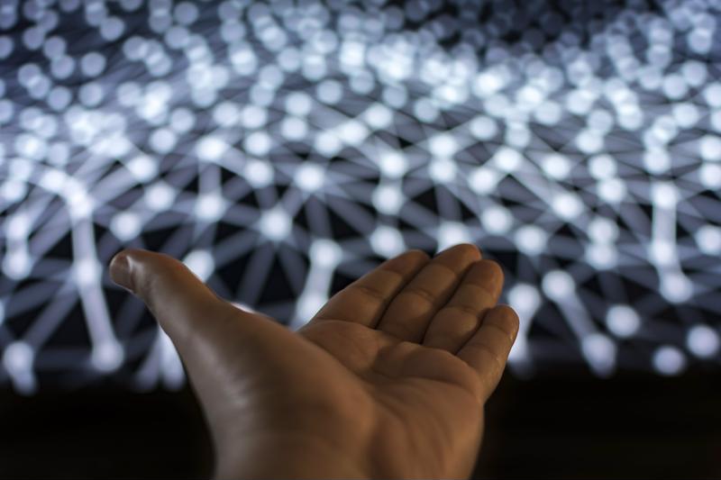 Hand reaching out to a network of connected dots.
