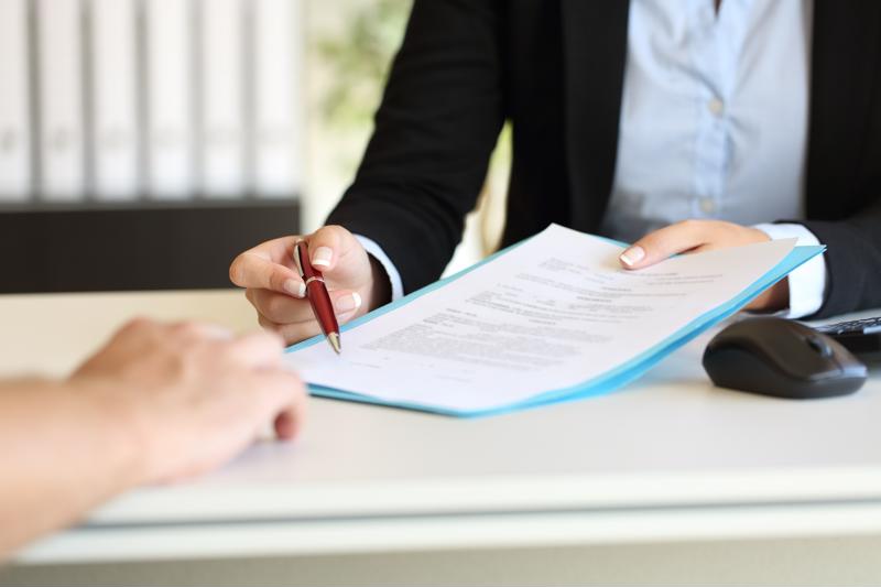 Hiring manager handing over paperwork to interviewee.